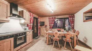 Een gezellige keuken met houten kasten, een fornuis en een eethoek met een tafel en stoelen.