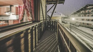 Een houten balkon met uitzicht op een besneeuwde straat en gebouwen.