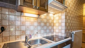 A kitchen with a double sink, wooden cabinets, a built-in oven, and a tiled backsplash.