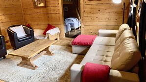 Ein gemütliches Blockhaus-Interieur mit einem Holzesstisch, zwei Sofas und einem kleinen Couchtisch.