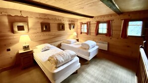 Ein Schlafzimmer im Chalet-Stil mit zwei Betten, einem Nachttisch und einem Fenster mit Vorhängen.