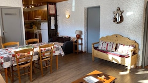 Een gezellige kamer met een houten eettafel, stoelen, een bank en een kleine tafel met een kom en een bord.