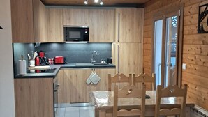 Una cocina moderna con armarios de madera, microondas, lavabo y comedor con mesa y sillas.