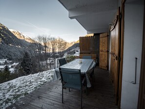An outdoor dining area with a table and chairs, overlooking a snowy landscape and mountains. - 2-Room Apartment in Châtel, Wifi, Pets Allowed, Parking (Châtel)