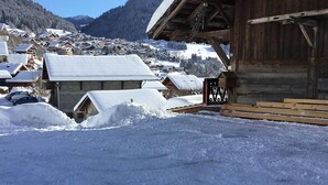 Un village enneigé avec des bâtiments en bois et une structure en bois portant une enseigne.