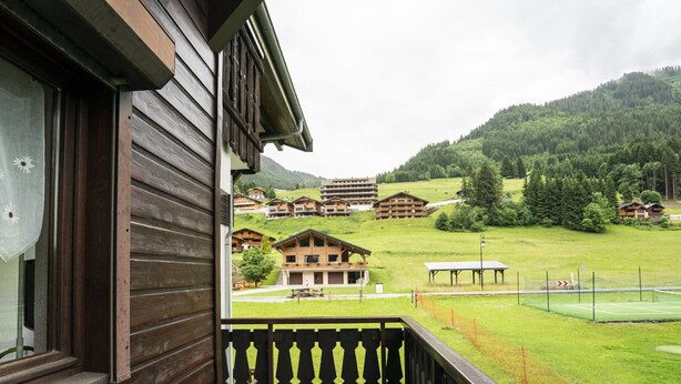 A wooden balcony overlooking a green field with buildings in the background. - Châtel Apartment 4 pax, Pets allowed, Balcony, Parking (Châtel)