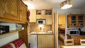 A compact kitchen with wooden cabinets, a microwave, and a refrigerator. - Châtel Apartment 4 pax, Pets allowed, Balcony, Parking (Châtel)