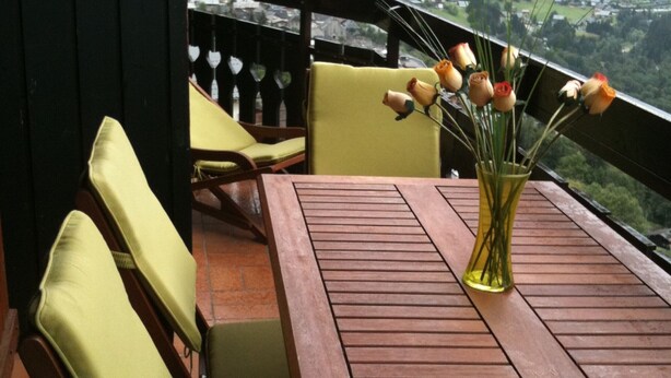 A wooden table with chairs, a vase with flowers, and a view of a green landscape. - 2-room apt for 5 people in Châtel with south-facing balcony (Châtel)
