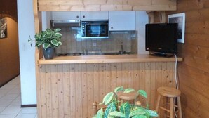 Keittiössä on puiset kaapit, mikroaaltouuni ja televisio, joka on sijoitettu puiseen työtasoon.
