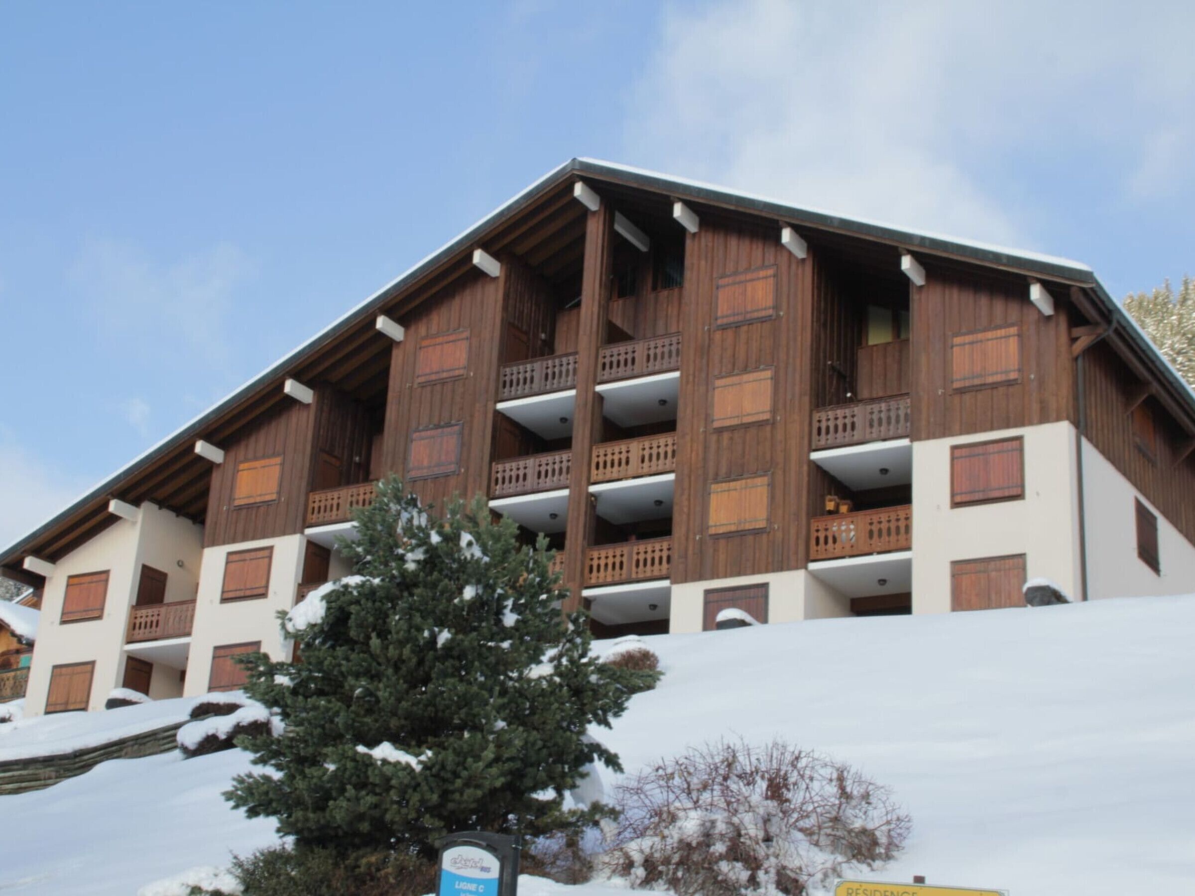 A multi-story building with wooden balconies and a snow-covered landscape.