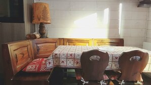 A room with a bed, two wooden chairs, a table, and a lamp.