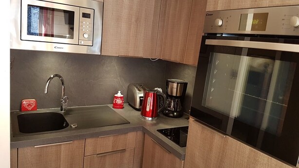A compact kitchen with a microwave, toaster, coffee maker, and oven.