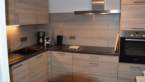 Eine moderne Küche mit Holzausstattung, Edelstahlgeräten und einem eingebauten Ofen.