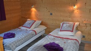 Ein Zimmer mit zwei Einzelbetten, Holzwänden und Wandleuchten.