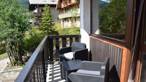 Ein Balkon mit Korbmöbeln und Blick auf einen Berg und Gebäude.