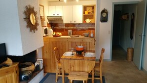 A cozy kitchen with wooden cabinets, a dining table set for two, and a television on a stand.