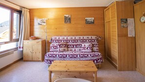 A cozy room with a wooden bed, a small table, and a window with curtains.