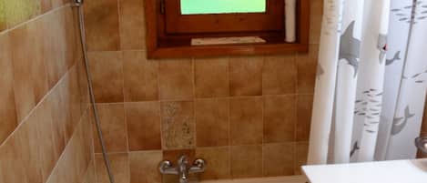 A bathroom with a bathtub, a shower, and a window with a frosted glass pane.