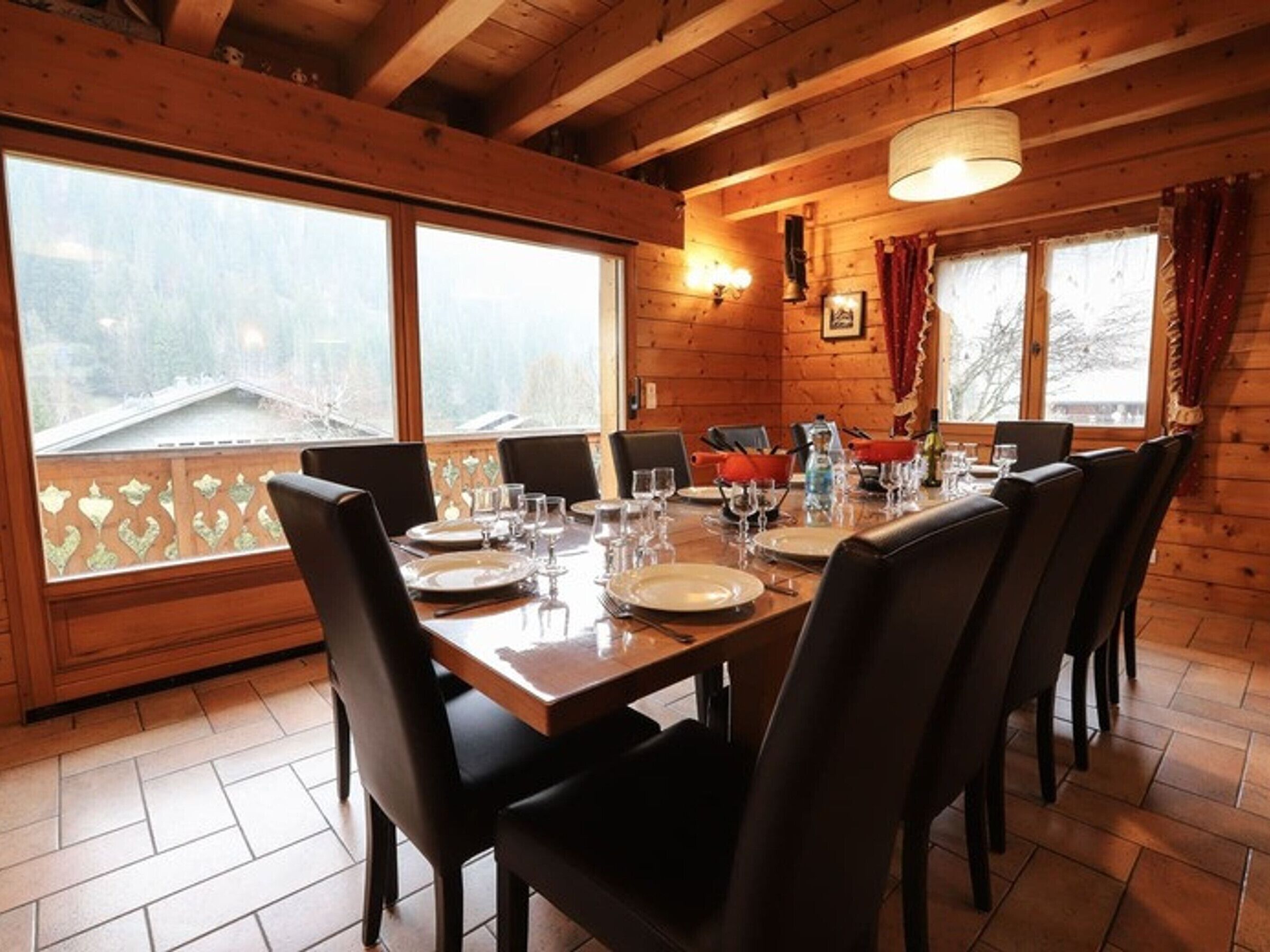 A wooden dining room with a large table set for six, surrounded by chairs.