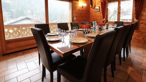 Comedor de madera con una mesa grande dispuesta para seis personas, rodeada de sillas.