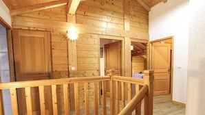 Un interior de madera con una escalera, puertas de madera y una lámpara.