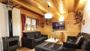 Una sala de estar acogedora con chimenea, dos sofás, una mesa de centro y un televisor montado en la pared.