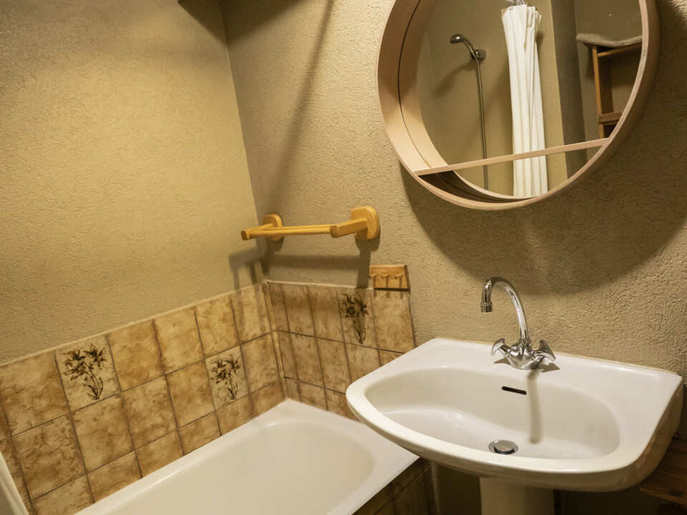 A bathroom with a white sink, a mirror, and a towel rack.
