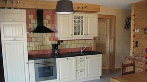 Una cocina con armarios blancos, estufa negra y salpicadero de azulejos.