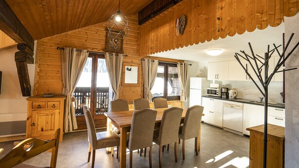 A wooden cabin interior with a dining area, kitchen, and a decorative metal sculpture. - 3-room apartment in Châtel for 7, near lift, pets allowed (Châtel)