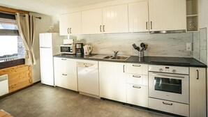 A modern kitchen with white cabinets, a built-in oven, a microwave, and a coffee maker. - 3-room apartment in Châtel for 7, near lift, pets allowed (Châtel)