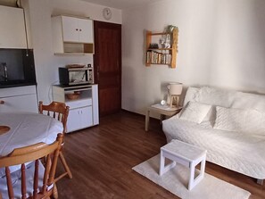 A compact living space with a kitchenette, a dining area, and a bed.