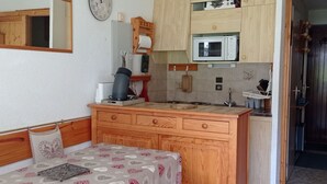A compact kitchen with a microwave, wooden cabinets, and a small sink.