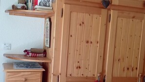 A wooden wardrobe with two doors, a small shelf with decorative items, and a drawer unit.