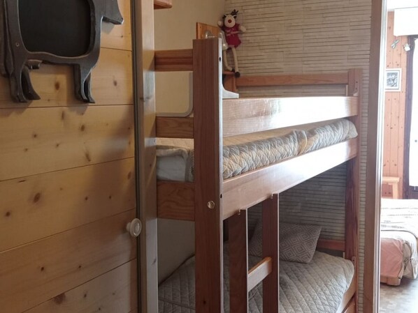 A bunk bed with a wooden frame and a quilted mattress.