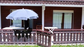 A two-story building with a balcony featuring a table and an umbrella.