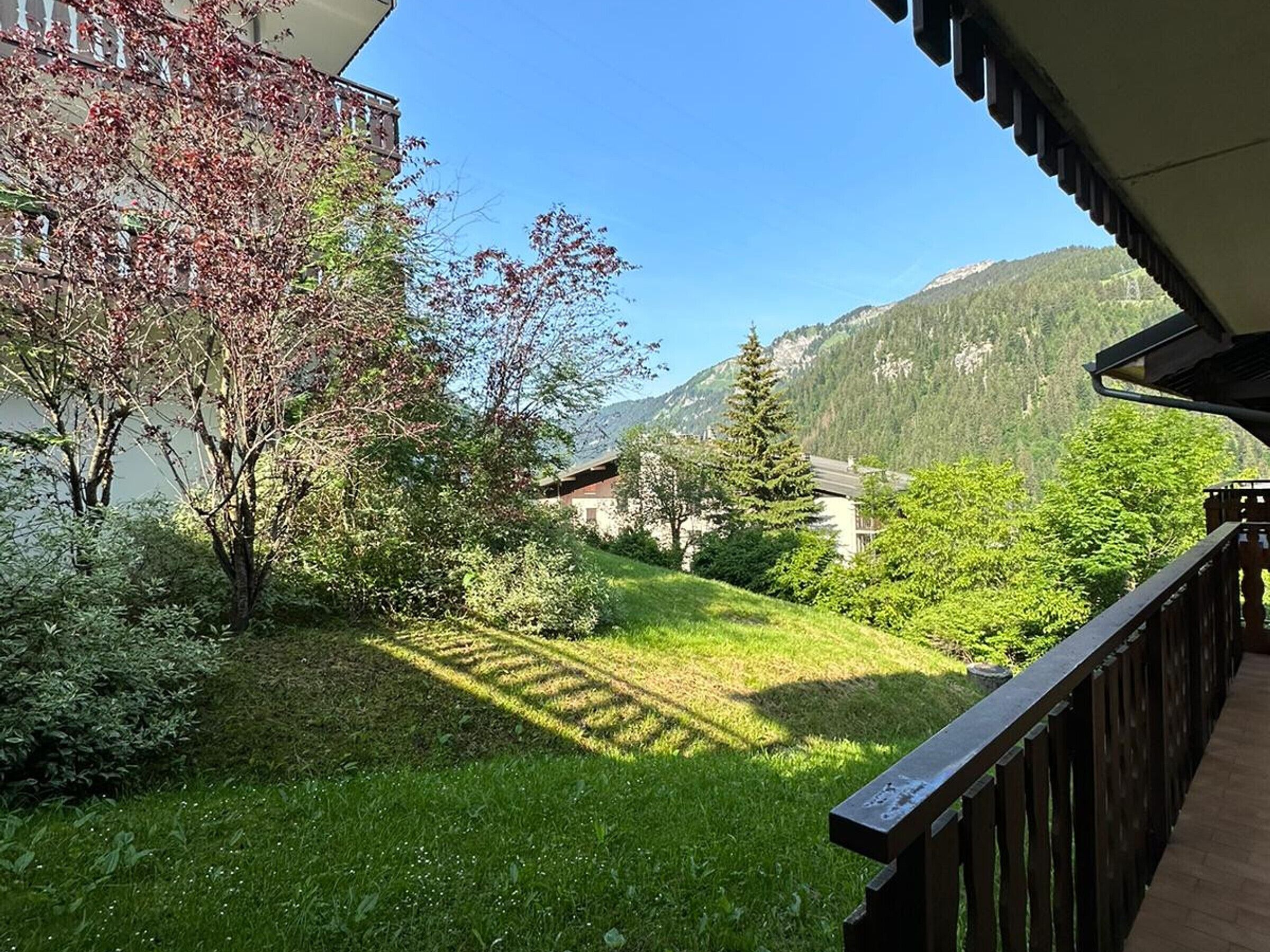 Un balcón con vistas a una montaña, un lago y un edificio de techo inclinado.