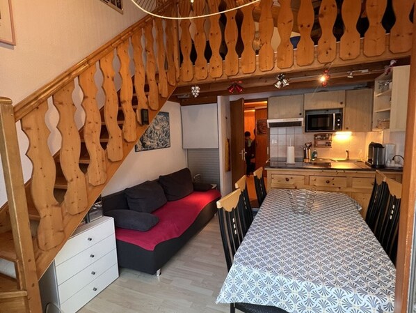 A compact living space with a sofa, a dining table, and a kitchen area.
