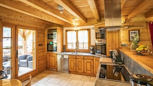 A wooden cabin kitchen with a central island, built-in oven, and a large window. - Spacious Chalet in Châtel, 8 bedrooms, jacuzzi, near slopes (Châtel)