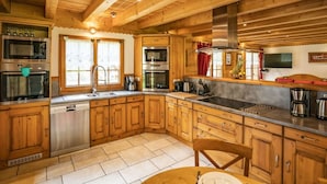 A wooden cabin-style kitchen with built-in appliances, a large window, and a dining area. - Spacious Chalet in Châtel, 8 bedrooms, jacuzzi, near slopes (Châtel)