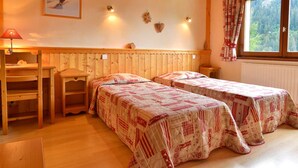 Ein gemütliches Zimmer mit zwei Betten, einem Schreibtisch und einem Fenster mit Vorhängen.