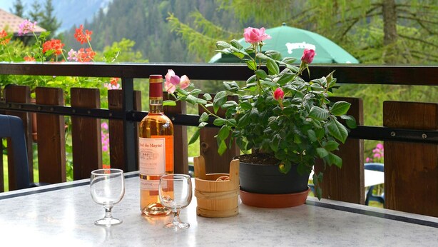 Ein Tisch mit einer Rosé-Weinflasche, zwei Weingläsern und einem Topf mit rosa Blüten.
