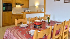 Eine gemütliche Küche mit Holdekor, einem eingebauten Backofen und einem für vier Personen gedecktem Esstisch mit rotem Tischlauf.