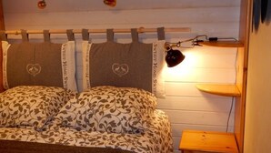 A bedroom with a bed, a bedside table, and a headboard with heart-shaped pillows. - Châtel Apartment 4 ppl, balcony, parking, pets allowed (Châtel)