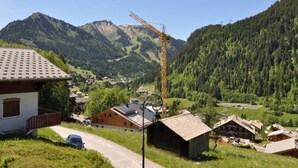 A rural village with traditional wooden houses, a clear mountain backdrop, and a construction crane. - Châtel Apartment 4 ppl, balcony, parking, pets allowed (Châtel)
