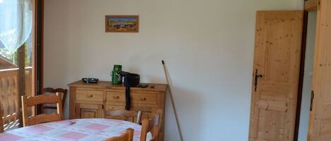A room with a wooden table and chairs, a painting on the wall, and a door.