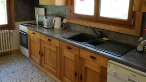 Cozinha com armários de madeira, máquina de lavar louça Bosch, micro-ondas, chaleira e fogão a gás.