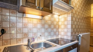 Una cocina con un lavamanos doble, armarios de madera, horno empotrado y salpicadero de azulejos.