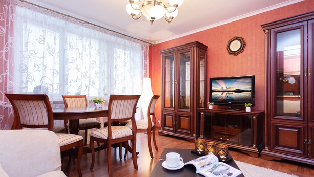 A living room with a dining table, chairs, a television, and a cabinet. - Comfortable apartment (Minsk)