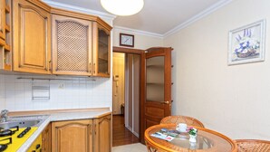 A kitchen with wooden cabinets, a yellow stove, and a dining area with wicker chairs and a glass table. - Comfortable apartment (Minsk)