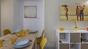 A dining area with a wooden table, yellow chairs, and a white console with a potted plant. - Raibetta Apartment by Wonderful Italy (Genoa)